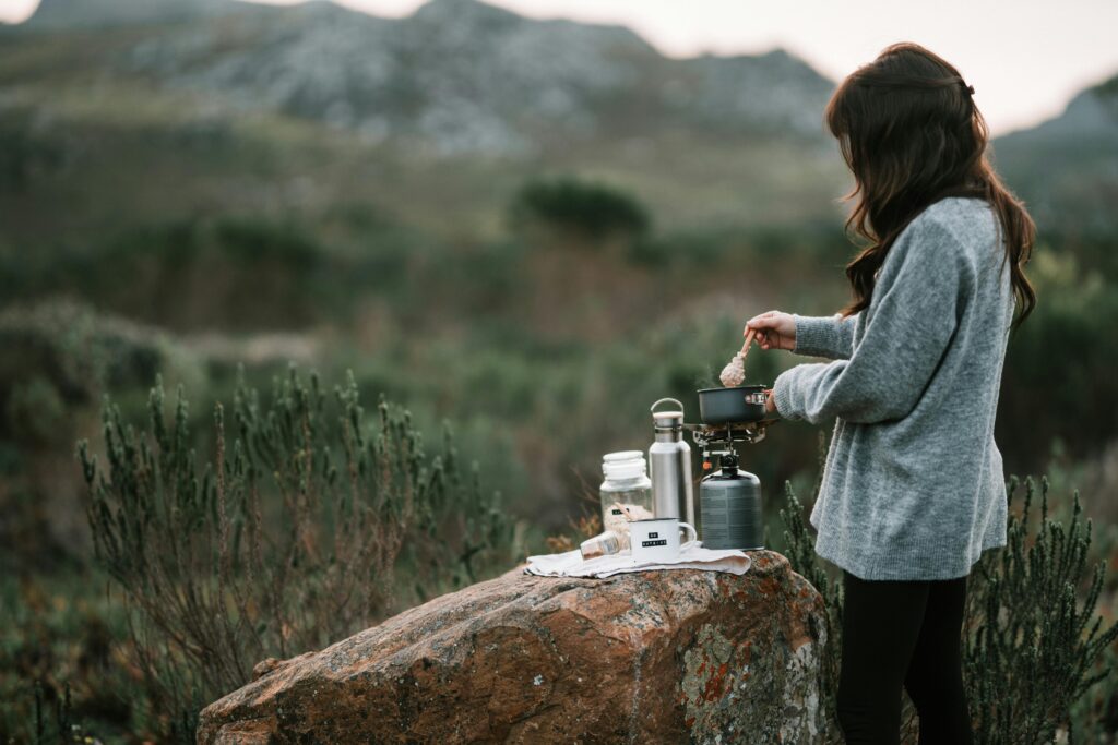 Cooking Solo Camping - A woman stirring a pot on a portable cooking stove.